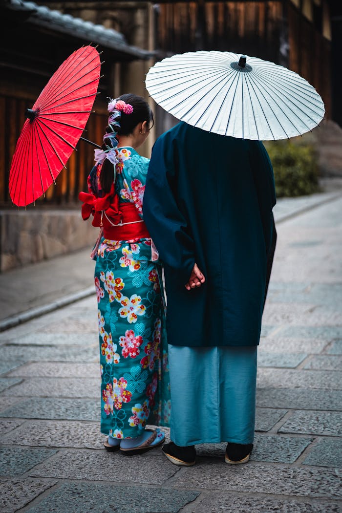 A couple wearing traditional kimonos and umbrellas walking in Kyoto, Japan.